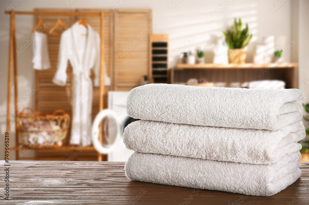 Folded clean towels on wooden table in laundry room, space for text Folded clean towels on wooden table in laundry room, space for text