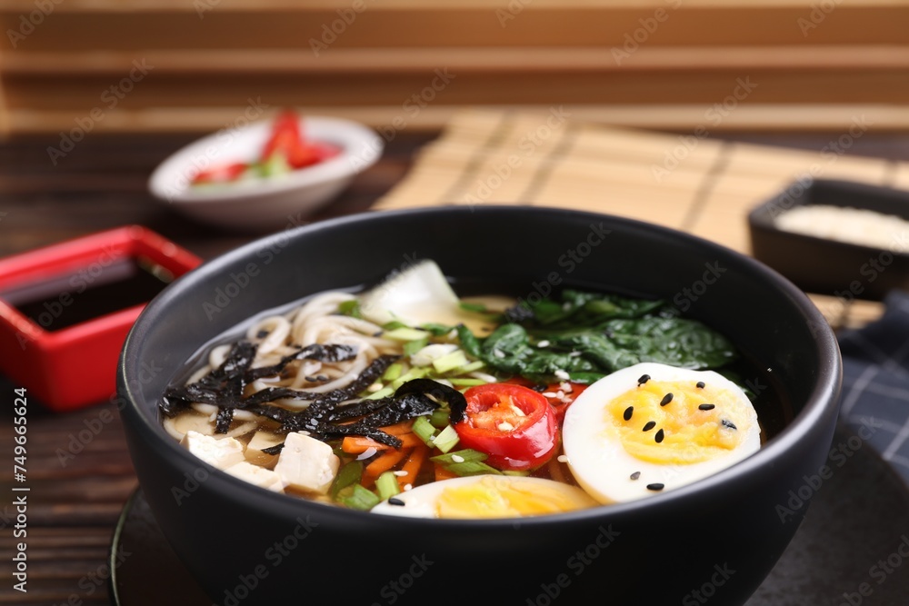 Delicious vegetarian ramen with egg, tofu and vegetables in bowl on table, closeup. Noodle soup Delicious vegetarian ramen with egg, tofu and vegetables in bowl on table, closeup. Noodle soup
