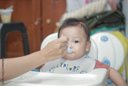 Asian mother feeding her 6 month old son.  photo