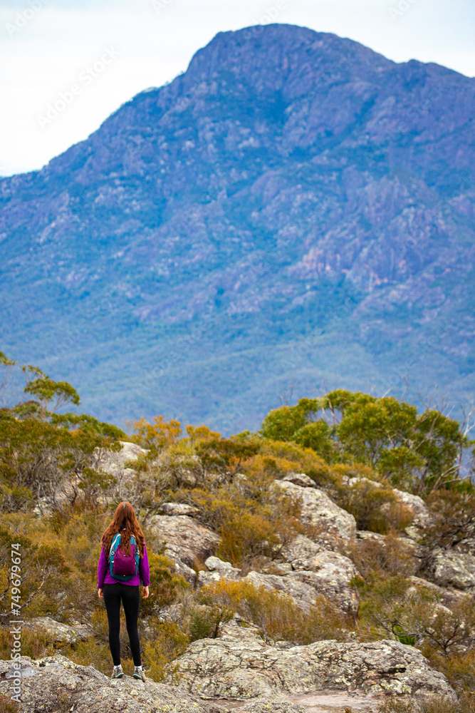 backpacker girl admiring the panorama of mountains in mount barney national park from the summit of mount maroon, queensland, australia