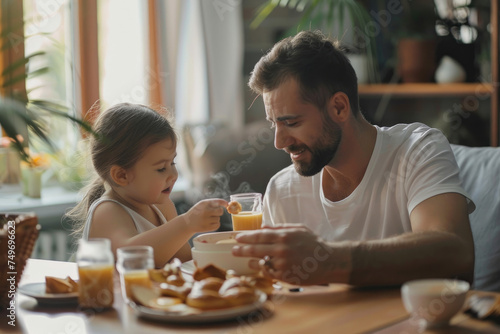 father feeds his daughter during breakfast at dining table