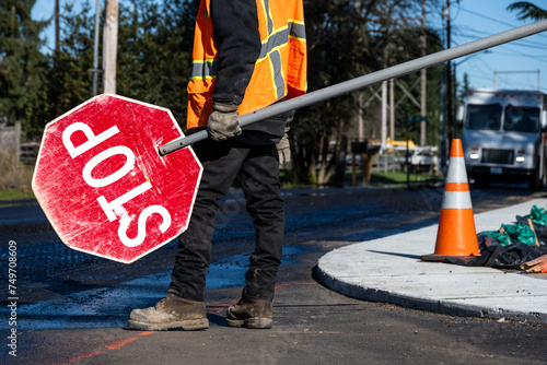 Fényképezés Traffic control worker in orange reflective safety vest with temporary stop sign