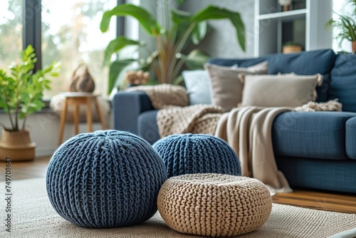 Two knitted poufs near dark blue corner sofa. Scandinavian home interior design of modern living room.