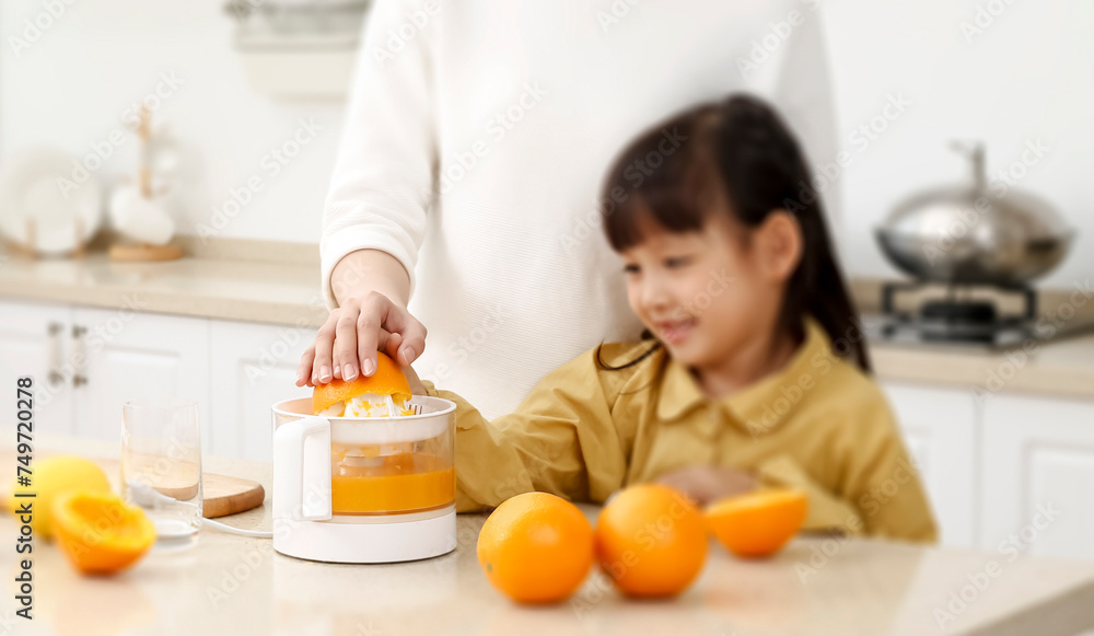 Making in the kitchen Asian mother making juice for daughter to drink
