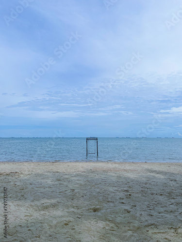 photo of a beach view with a cloudy sky and a swing in the middle of the beach
