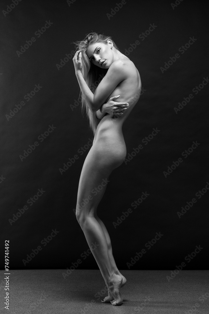 Naklejka premium Abstract fine-art portrait. Black and white photo of nude beautiful woman. Female body on black background.