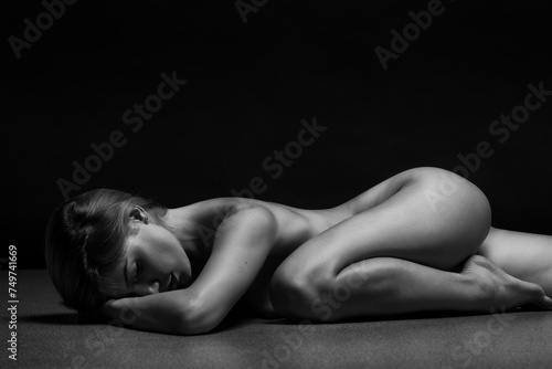 Abstract fine-art portrait. Black and white photo of nude beautiful woman. Female body on black background.	 photo
