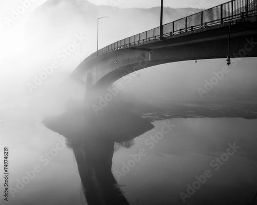 Mysterious bridge into mist over calm water reflection