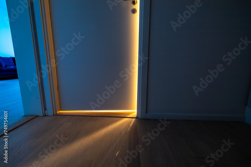 A door in an apartment left ajar at night with a light on. photo