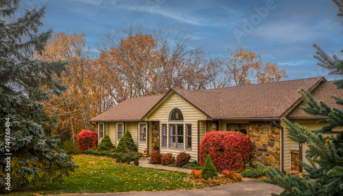 View of Midwestern suburban house in fall with front yard in foreground and blue sky in background