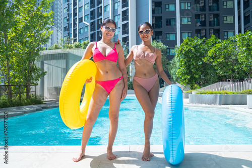 Foto Female friends in bikinis playing with colorful rubber rings by the pool