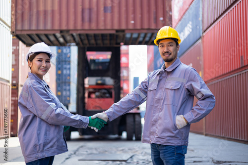 Engineers shaking hands congratulating themselves on success with shipping containers in the background. photo