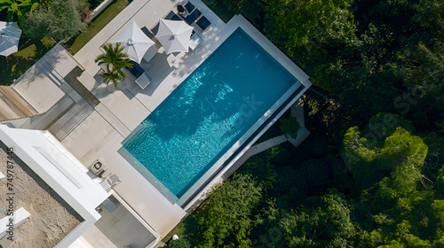 Serenity meets sophistication as a sleek modern residence harmonizes with a sparkling pool  creating an inviting haven for relaxation and leisure