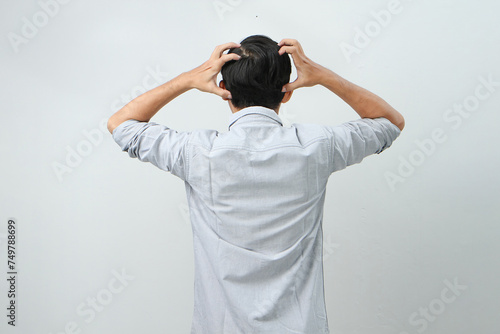 Fotografía back view of asian indonesian man with hand grab his head showing stressful confused gesture