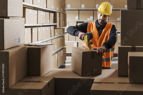 Warehouse worker sealing a box with tape photo