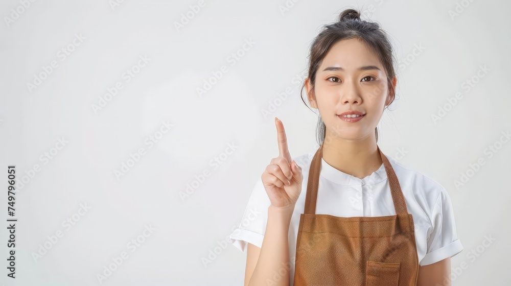 Portrait of Asian woman workers fresh market with brown apron standing and pointing finger to something isolated on white background Portrait of Asian woman workers fresh market with brown apron standing and pointing finger to something isolated on white background