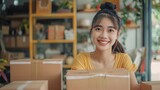 Young attractive asian woman owner startup business look at camera work happy with box at home prepare parcel delivery in sme supply chain, procurement,