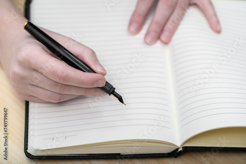 Długopis trzymany  w dłoni nad otwartym zeszytem w linie z bliska © Paweł Kacperek