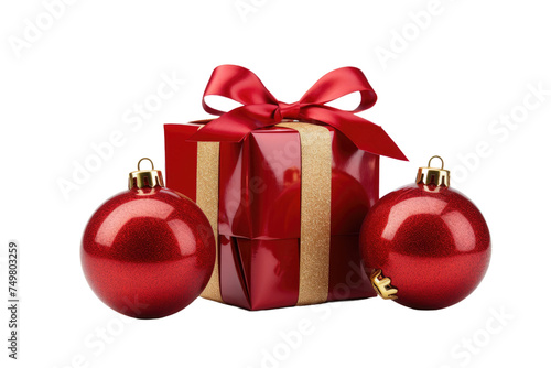 Red Gift Box With Bow and Ornaments. A red gift box with a shiny red bow sits next to two red ornaments. The box is wrapped in glossy paper  and the bow is neatly tied on top.