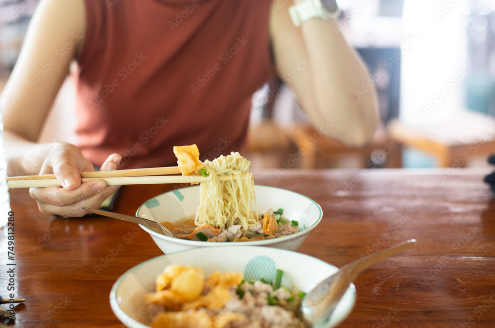 Woman hands holding delicious egg noodle with chopsticks