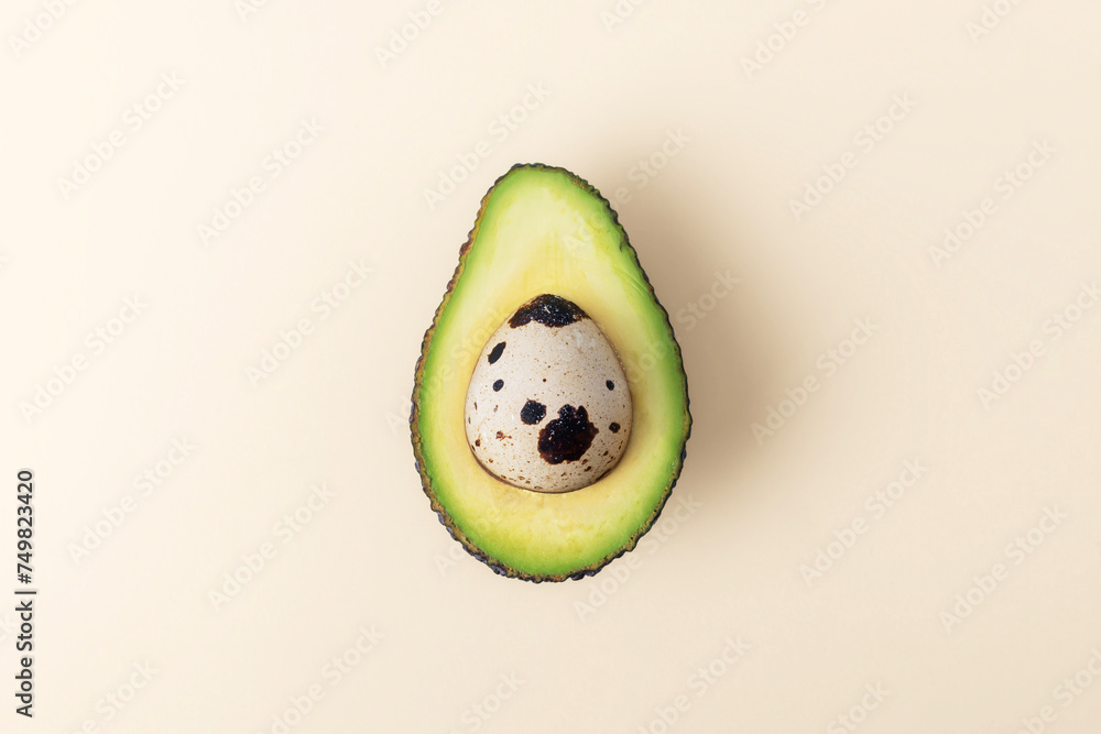 Easter Concept. Egg in cut avocado on beige pastel background.
