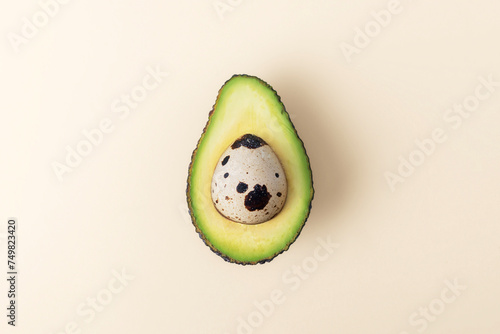Easter Concept. Egg in cut avocado on beige pastel background.