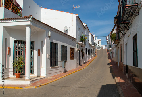 Casas blancas en las calles encaladas de un pequeño pueblo andaluz. La empinada calle Juan Ramón Jiménez de Sanlúcar de Guadiana. Andalucía, Huelva, España. 2019.