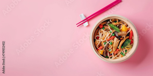 A bowl of food with chopsticks on a pink background