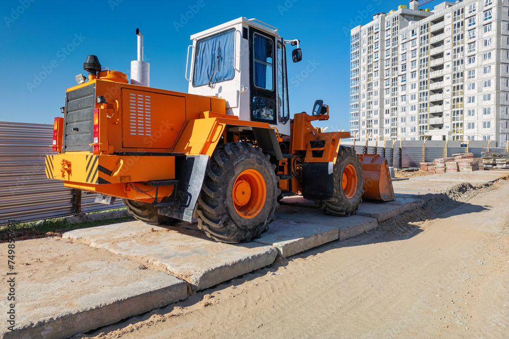 An orange and white construction vehicle is stationed on the side of a road, ready for work An orange and white construction vehicle is stationed on the side of a road, ready for work