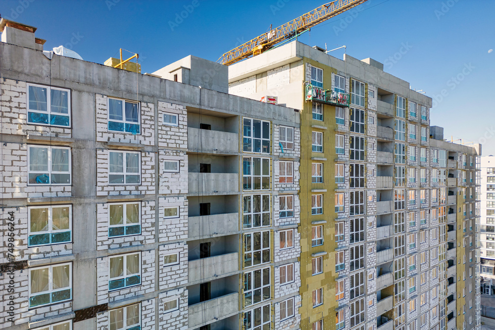 A tall building under construction with a crane on top, symbolizing ongoing development and progress in the urban landscape A tall building under construction with a crane on top, symbolizing ongoing development and progress in the urban landscape