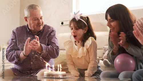 Family singing while a girl blowing the candles of her birthday cake photo