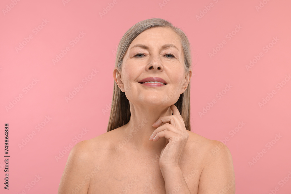 Beautiful woman touching her neck on pink background Beautiful woman touching her neck on pink background