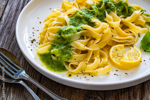 Tagliatelle with basil pesto sauce on wooden table 