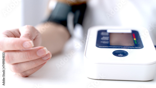 the girl measures blood pressure with a blood pressure monitor