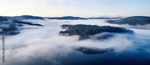 Aerial view of mountain peak with green trees in fog