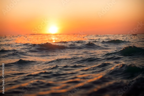 Calm waves reflect orange sunset in tranquil sea scene 