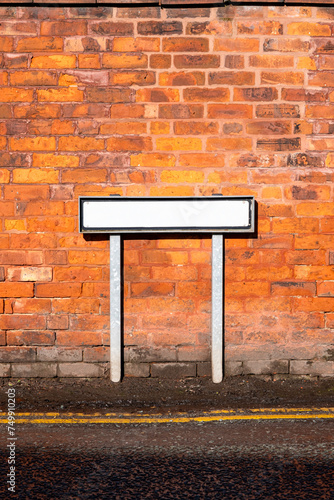 Blank street name sign against brick wall
