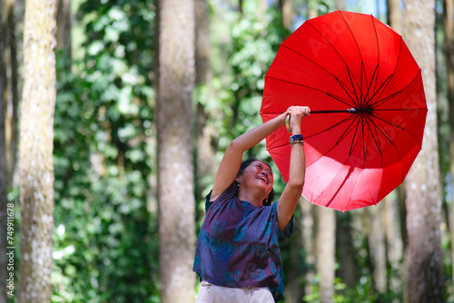 Woman's red umbrella blown away by the wind while walking alone in the park photo