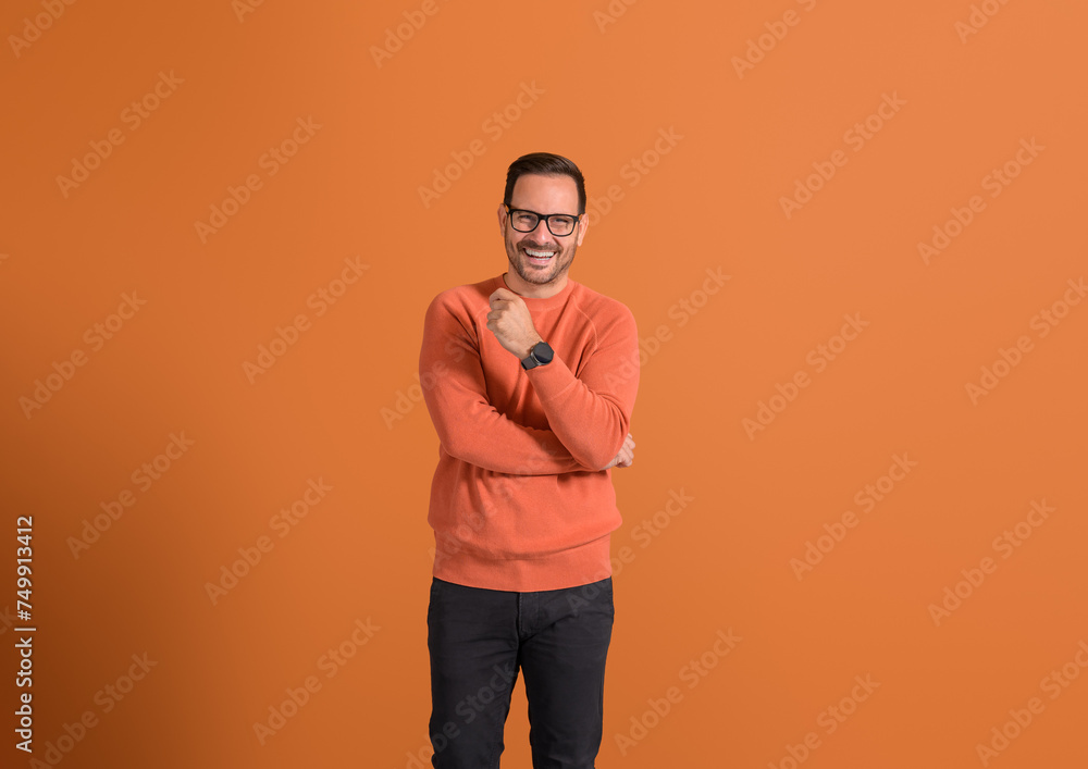 Portrait of positive young male professional smiling and posing confidently on orange background Portrait of positive young male professional smiling and posing confidently on orange background
