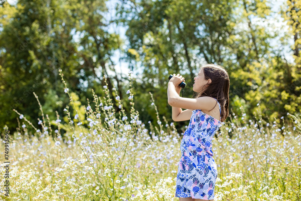 Adorable teenage girl looking at the sky on a walk in the park, holding binoculars in her hands. Adorable teenage girl looking at the sky on a walk in the park, holding binoculars in her hands.