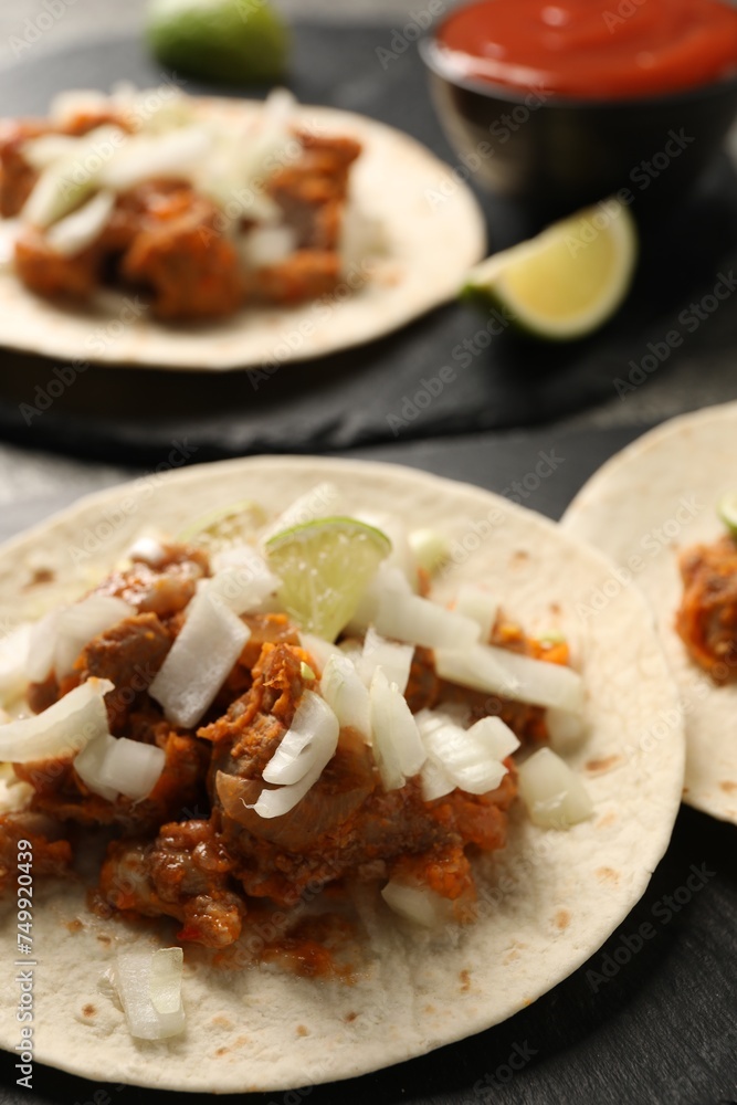 Delicious tacos with vegetables, meat and lime on dark table, closeup