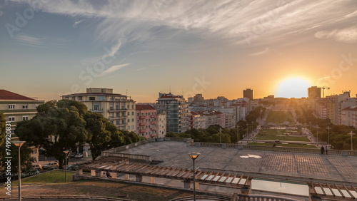 Panorama showing sunset over lawn at Alameda Dom Afonso Henriques and the Luminous Fountain aerial timelapse in Lisbon.