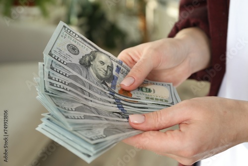 Money exchange. Woman counting dollar banknotes on blurred background, closeup