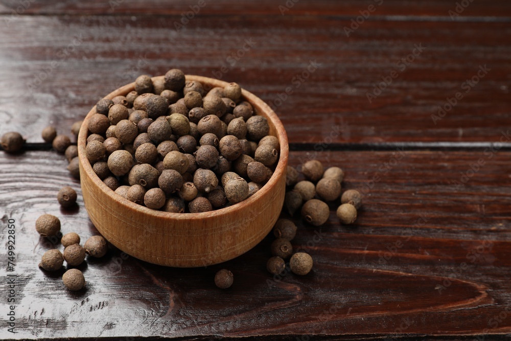 Dry allspice berries (Jamaica pepper)in bowl on wooden table, space for text Dry allspice berries (Jamaica pepper)in bowl on wooden table, space for text