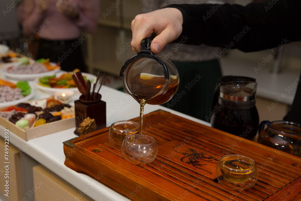 tea ceremony. a man pours tea from a glass teapot. Chinese traditions. green tea.