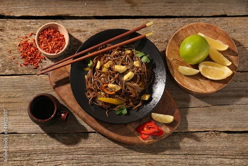 Stir-fry. Tasty noodles with vegetables and meat served on wooden table, flat lay