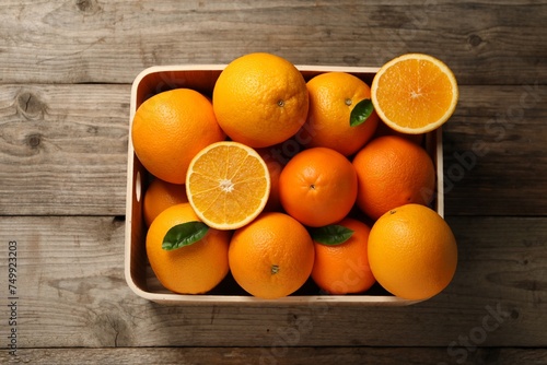 Many whole and cut ripe oranges on wooden table, top view