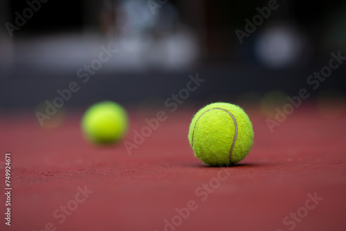 Yellow tennis ball on red court. Fluffy felt tennis ball closeup photo. Summer outdoor sport concept. © Mohammad