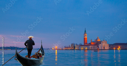 Venetian gondolier punting gondola through grand canal waters - View of San Giorgio Island in Venice with wooden buoys in Giudecca Canal 