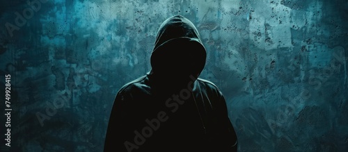 A mysterious hacker man in the hoodie in front of dark concrete background. Generated AI